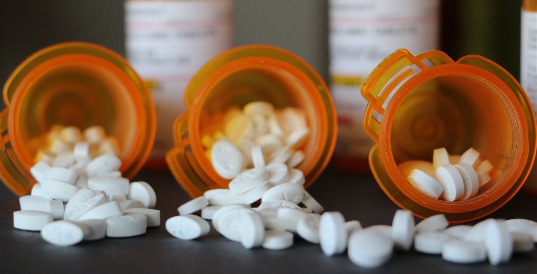 prescription-drugs-white-pills-spilling-out-of-prescription-bottles-with-prescriptions-in_t20_GGZXYY