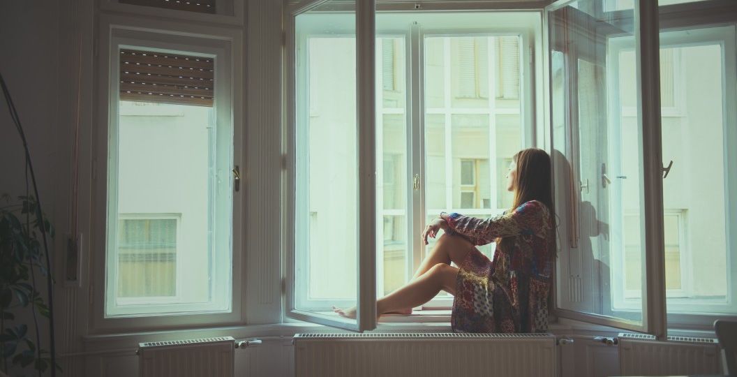 romantic-self-portrait-of-a-woman-sitting-on-a-window-in-a-white-cozy-apartment-with-city-view-and_t20_7mprN6
