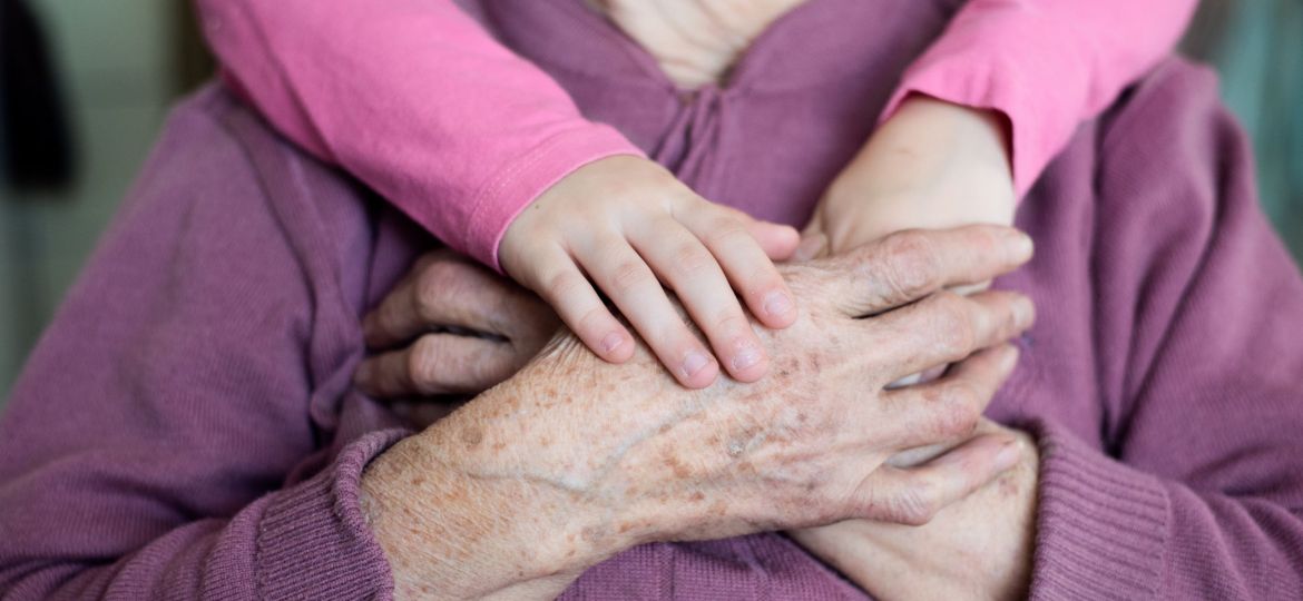 Unrecognizable granddaughter holding hands of her grandmother