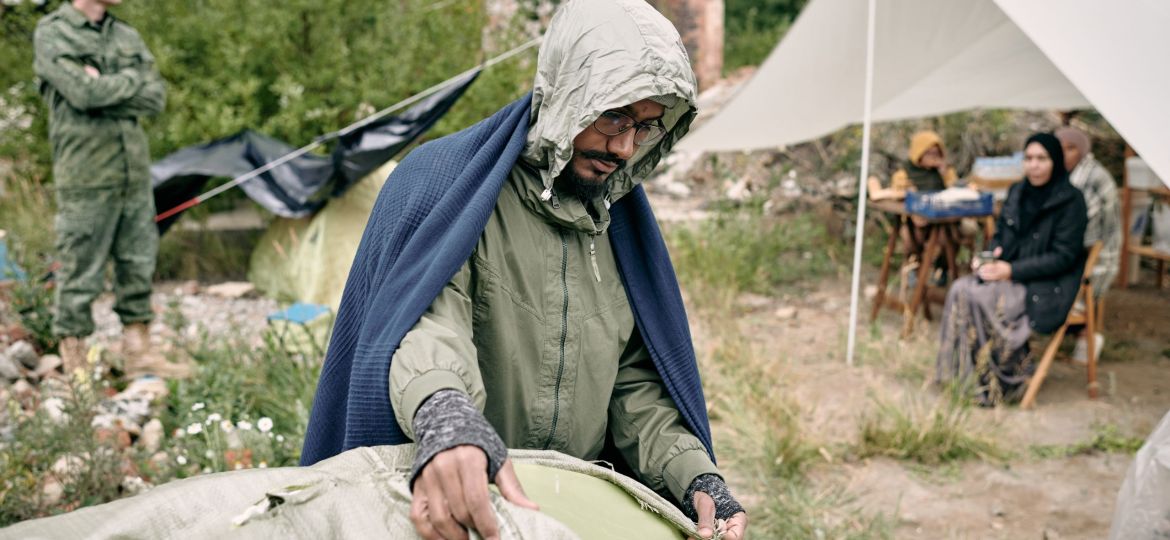 Refugee Man Covering Tent With Sack